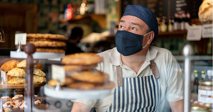 Propietario del negocio con mascarilla en su panadería 