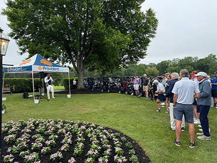 Golf event attendees standing around the Provident Bank tent