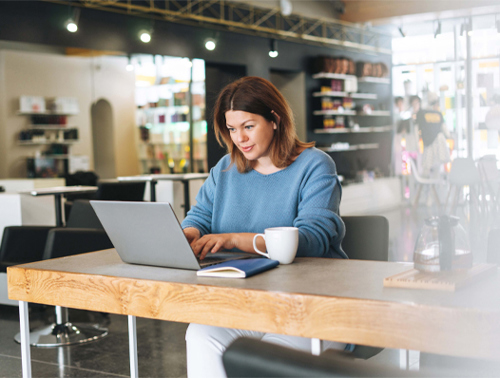 lady looking at computer with coffee cup on the side
